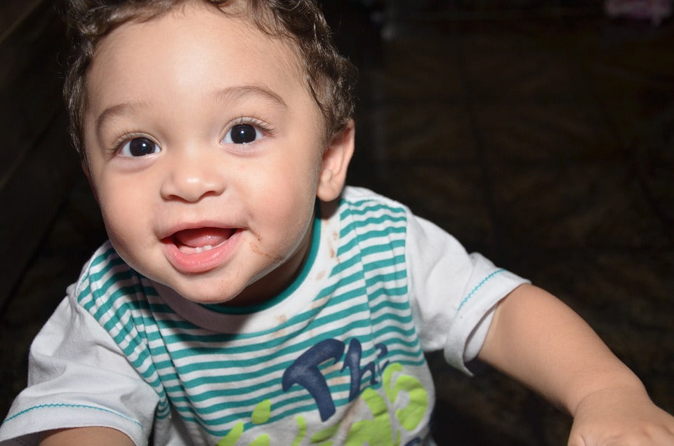 A one year old baby boy gives a big smile. By the end of the first year, your child will have made important strides in their language development.