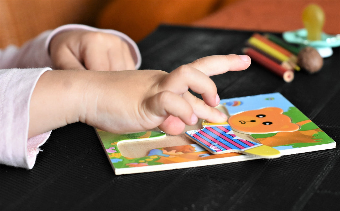 A pair of toddler hands complete a teddy bear puzzle. Puzzles are one of many quiet-time activities toddler will love to engage in.